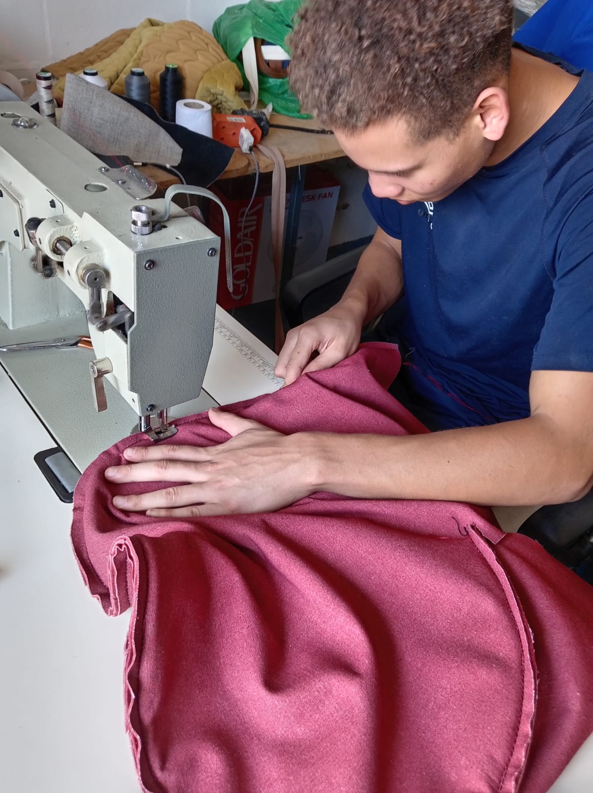 Apprentice sewing upholstery fabric in the workshop
